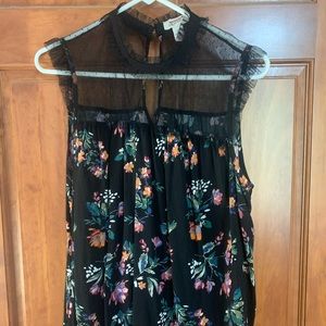 This is a black top with flowers on it with a mesh top.
